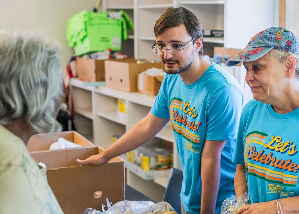 Young man and older woman volunteering in food pantry and engaging with Common Ground client