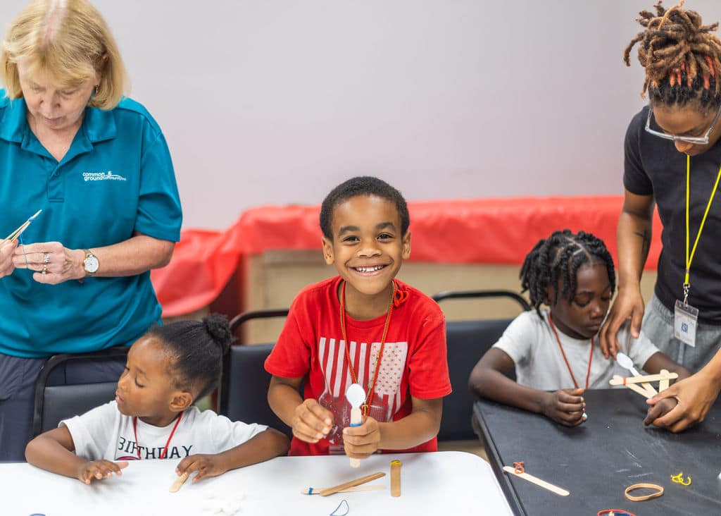 Young boy smiling as he makes a craft at Common Ground Community Shreveport